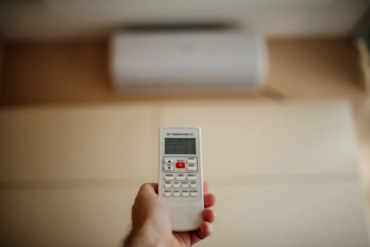 Afstandsbediening met een vaste split-airco op de achtergrond