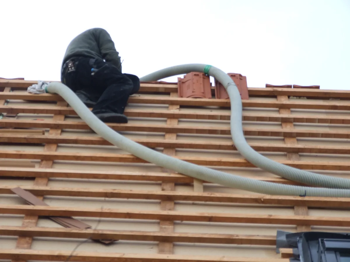 Cellulose wordt via een slang in de dakconstructie ingeblazen.
